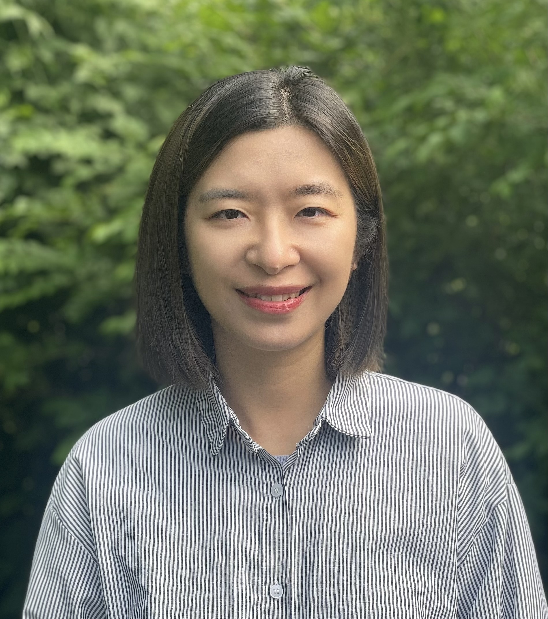 Jeanine White smiling in a red plaid shirt and tortoise shell glasses